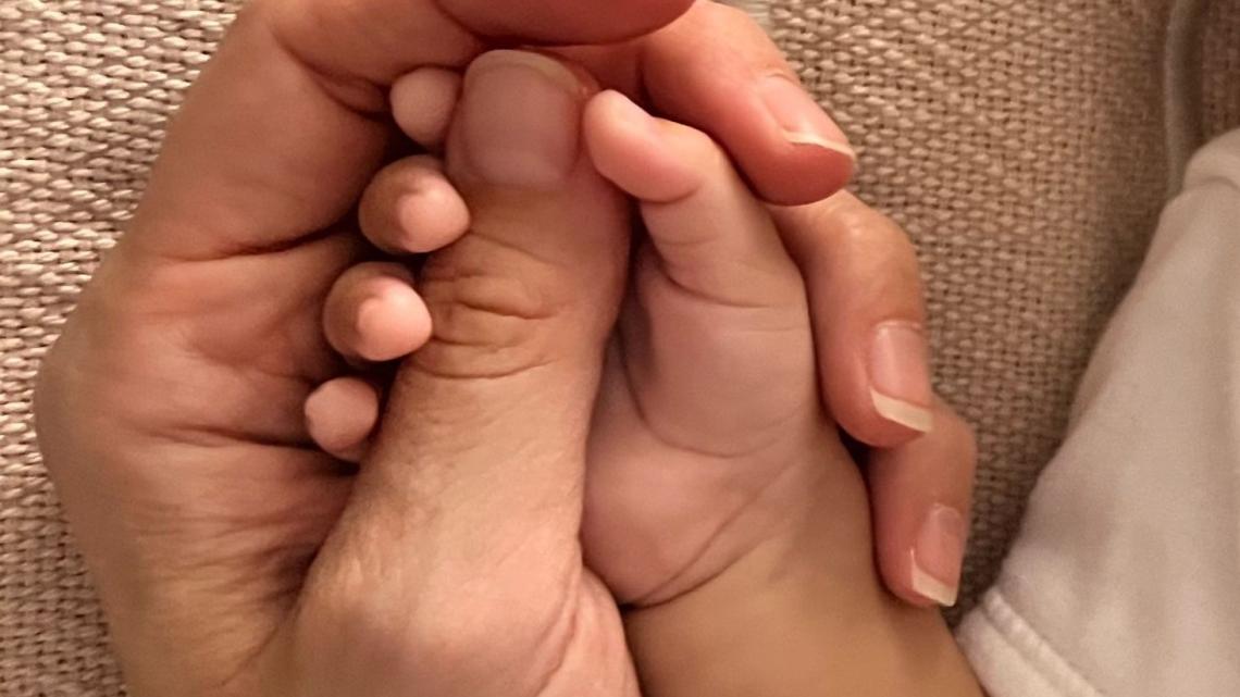 es veu la mà d'una mare agafant la mà d'un nadó